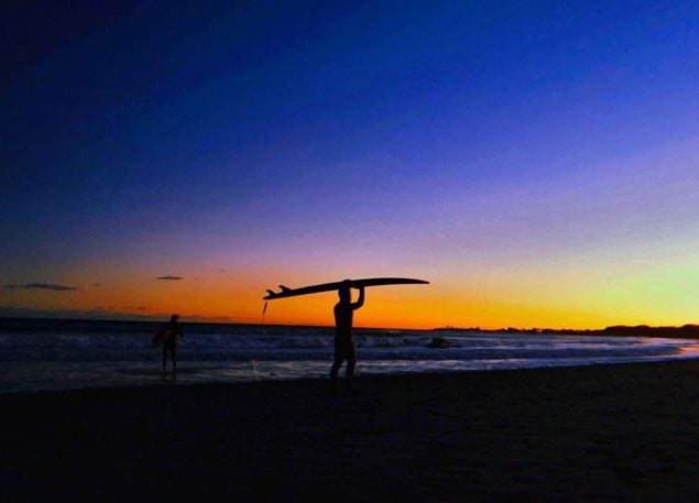 Instagram image of a surfer carrying a board over his head at sunset