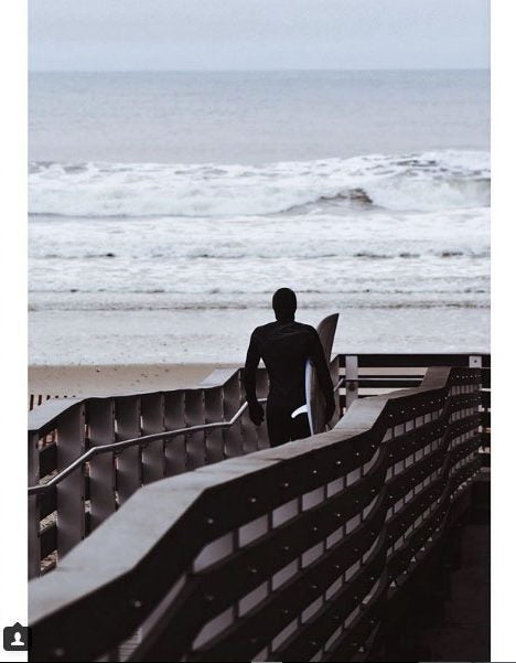 Instagram image of a surfer with a board walking toward the water