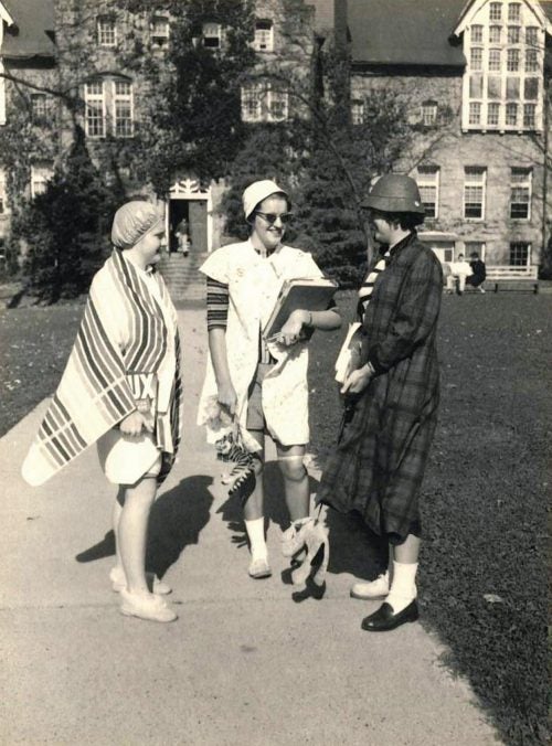 An old black and white taken in 1956 of three oddly dressed women on the URI Quadrangle