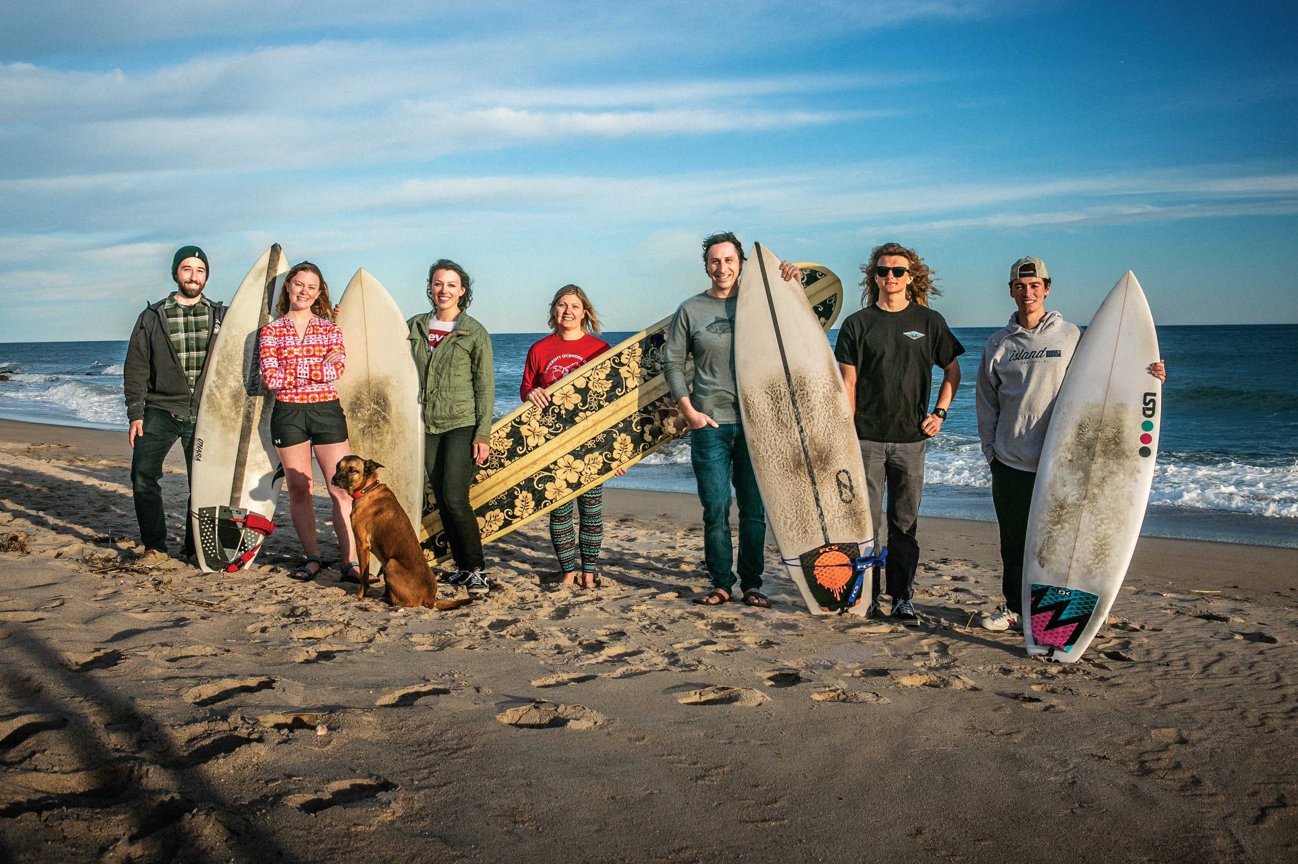 URI students and faculty posing with surf boards at Narragansett beach