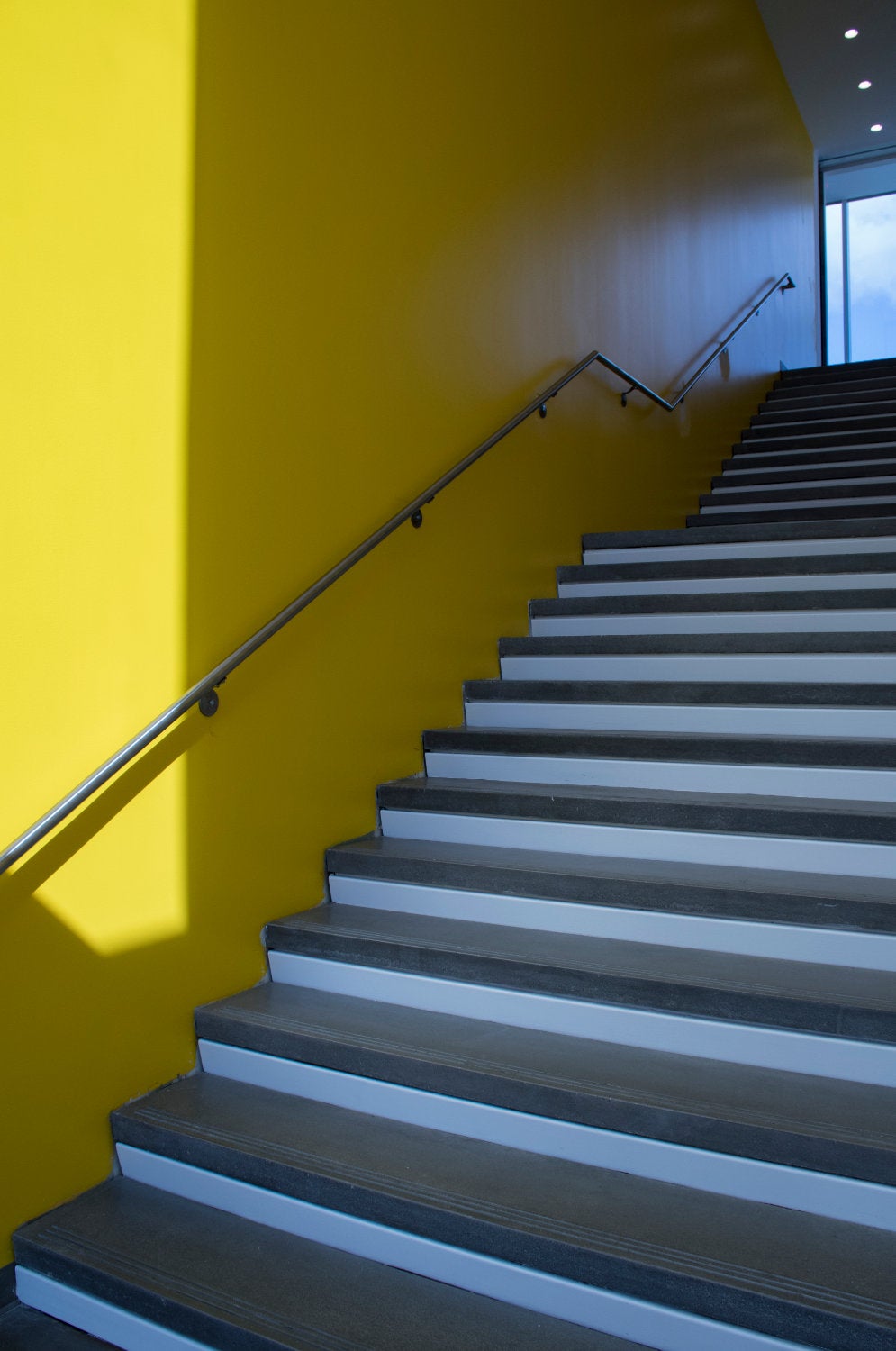 A staircase accented by a vivid yellow wall.