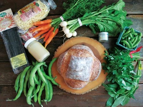 Fresh cooking ingredients spread out around a loaf of freshly baked bread