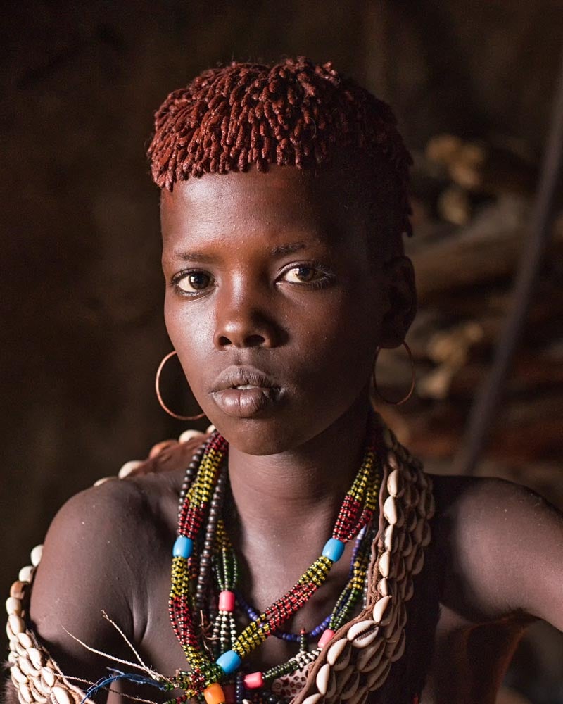 A portrait of a young woman wearing a necklace of cowrie shells and colored beads