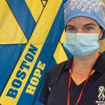Kim Daly wearing PPE in front of a Boston Hope flag