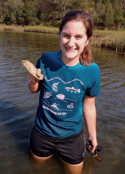 Rebecca Stevick standing in water holding an oyster