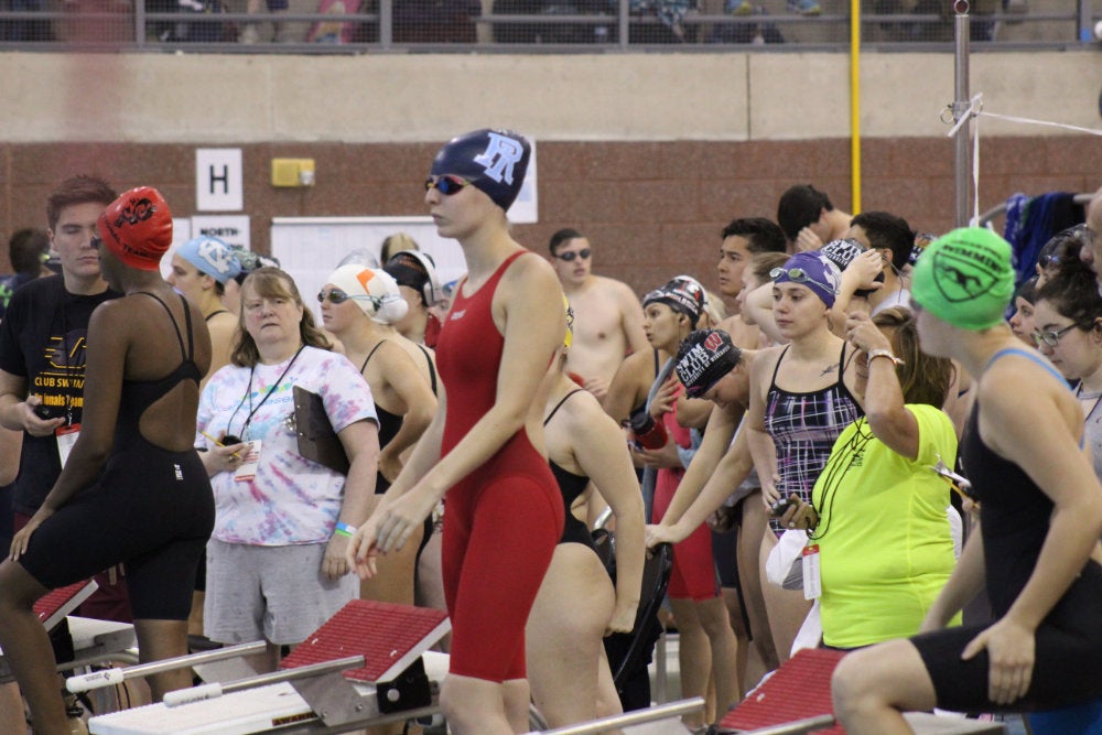 Swimmers getting ready at their diving blocks during a meet.