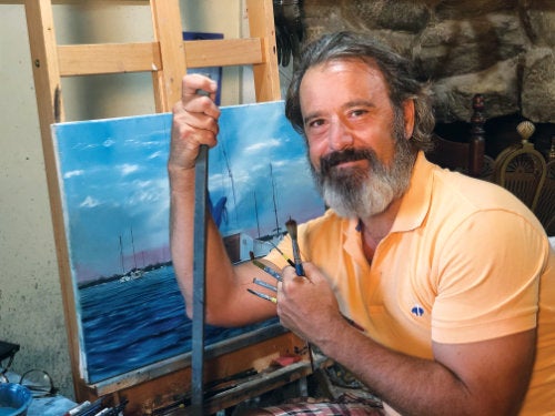 Eric Lutes seated next to an easel with a canvas