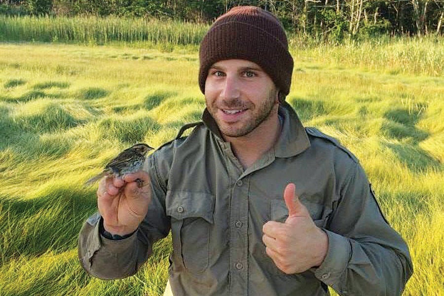 Ryan Kleinert giving the thumbs up with a Saltmarsh Sparrow perched on his hand