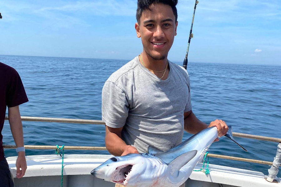 Marine Biology major, Dario Castillo holding a shark on a research vessel