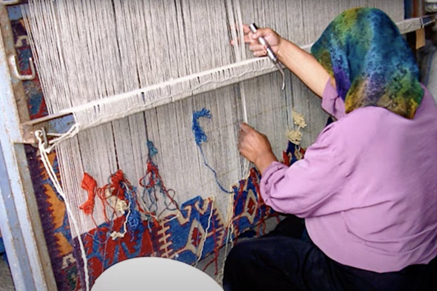 A picture of a woman weaving a geometric patterned textile