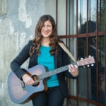 Nicole O'Malley, Assistant Clinical Professor of Music Therapy at URI holding a guitar