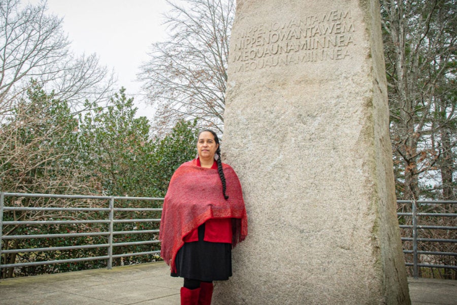 Loren Spears, executive director of the Tomaquag Museum, stands in front of the granite monolith in front of the Robert L. Carothers Library and Learning Commons.