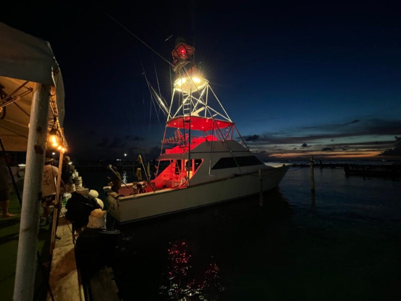 A motorboat at the dock with red running lights at night
