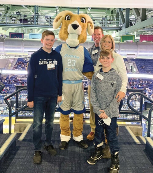 David and Cortney Nicolato posing with Rhody and their two children at a URI athletic event