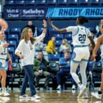 URI women's basketball players high-fiving their coach Tammi Reiss on the court