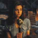 Aria Mia Loberti holding a microphone in a still image from the Netflix series All the Light We Cannot See