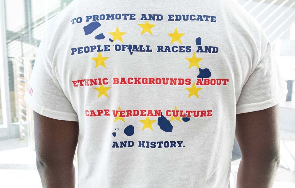 Member of CVSA wearing a white t shirt that reads "To promote and educate people of all races and ethnic backgrounds about Cape Verdean culture and history."