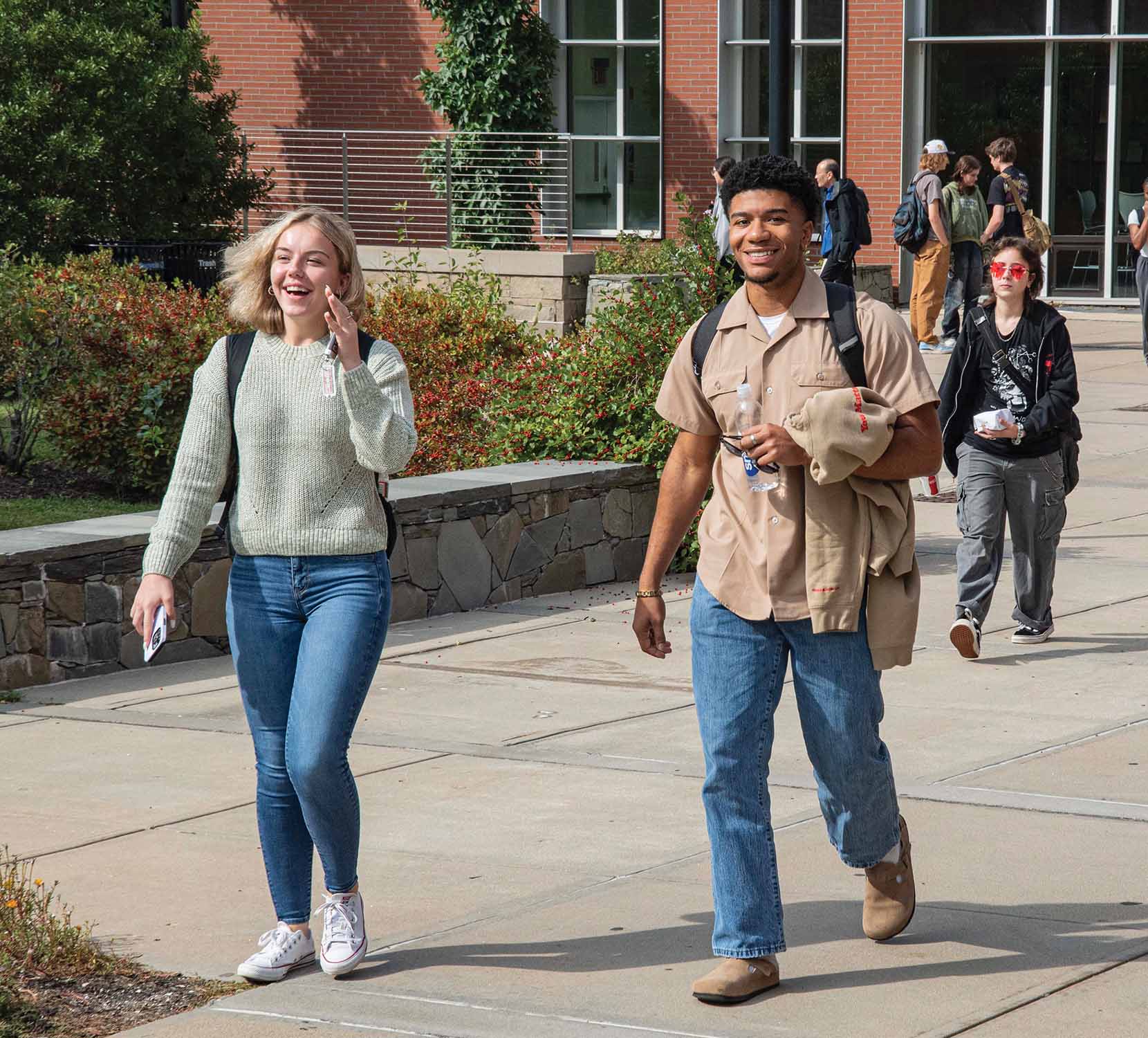 A male and female student smiling and walking together on the URI campus.