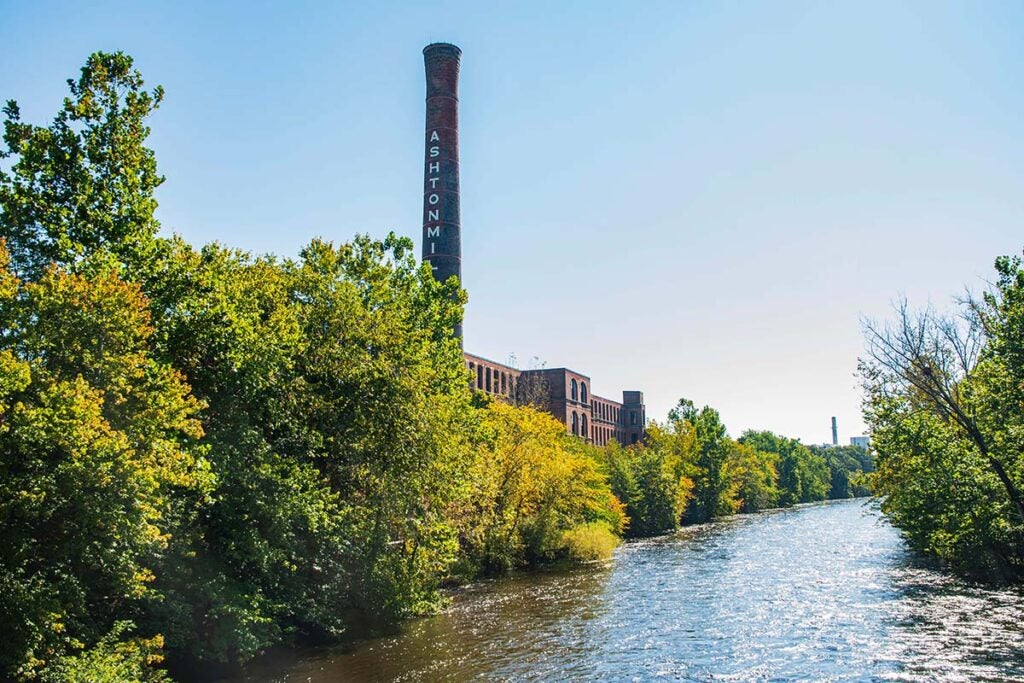 Wide view of the Blackstone River flowing past the industrial Ashton Mill building and tower