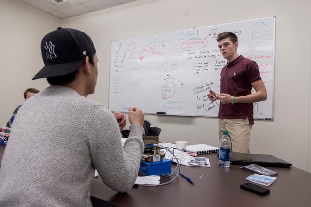James Gannon, standing, of Coventry, R.I, a sophomore studying electrical engineering and Spanish responds to his teammate, Long Zou of Westerly, R.I., a sophomore studying electrical engineering at the Makerspace on the University of Rhode Island Kingston Campus on Oct. 15, 2016, during HealthHacks RI, a health and wellness hack-a-thon. (URI photo by Michael Salerno Photography)