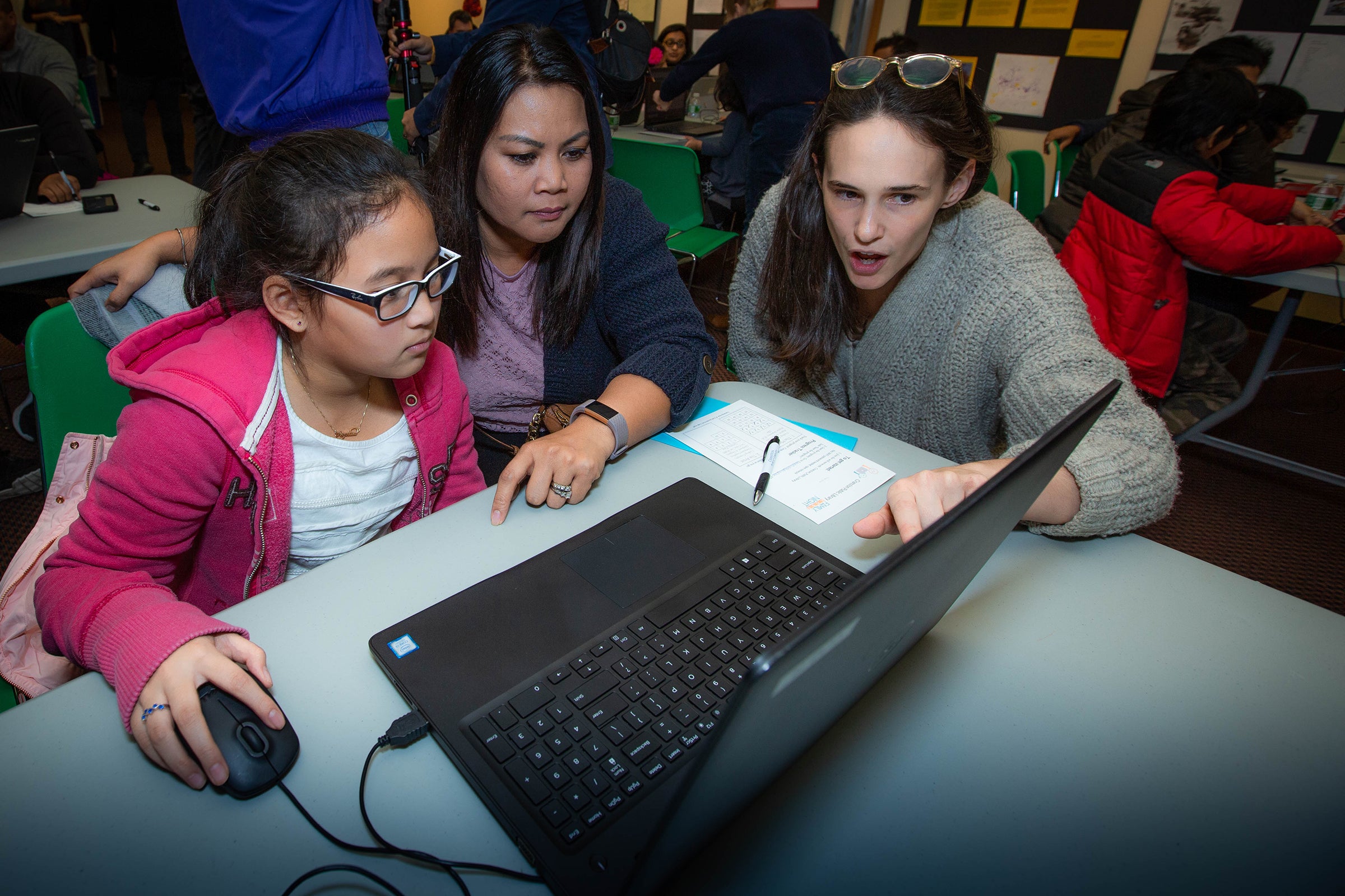 A student and her mother are coached by a URI Graduate School of Library and Information Sciences (right) .