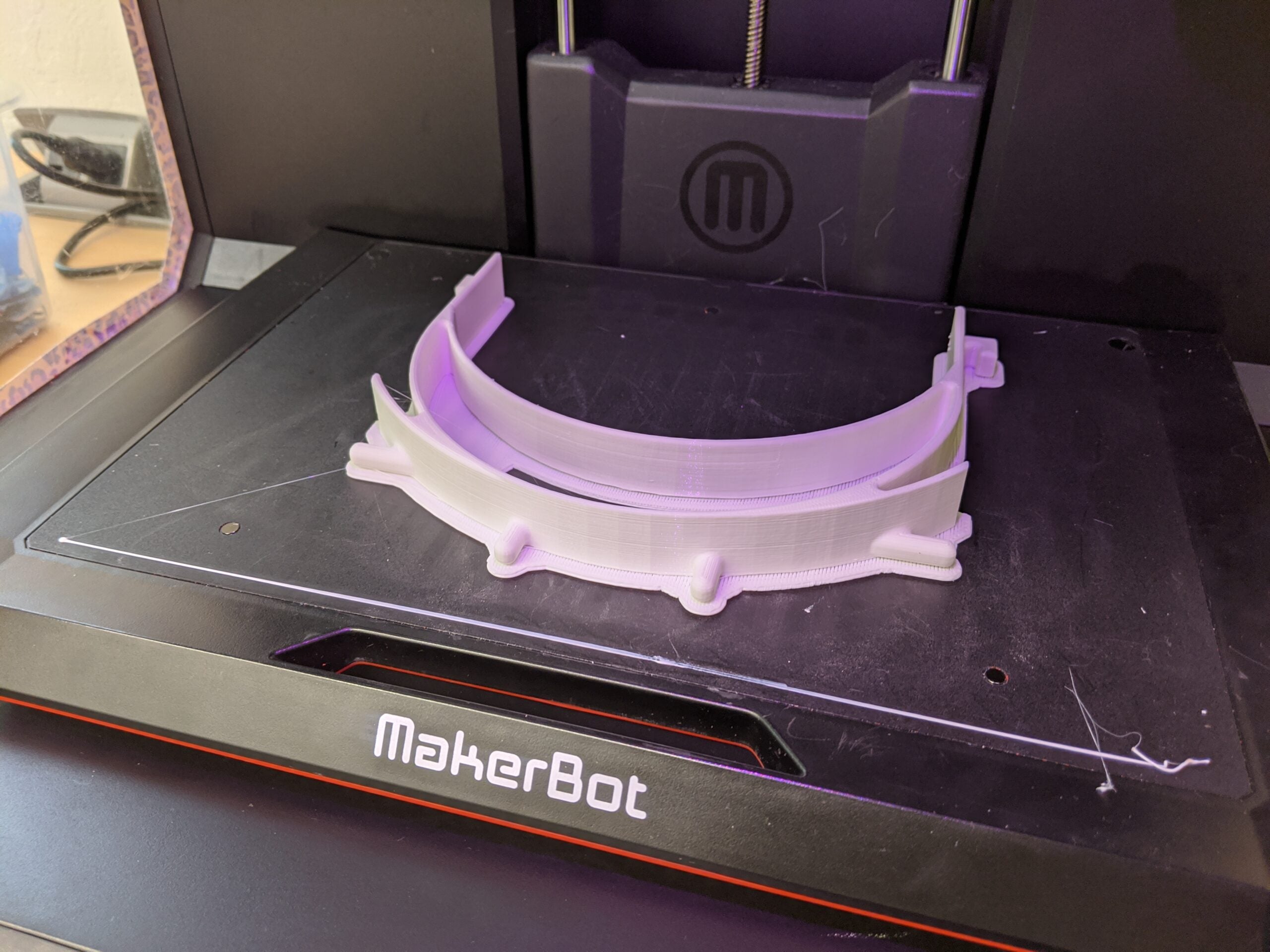 Plastic bands for protective face shields rest on a 3-D printer