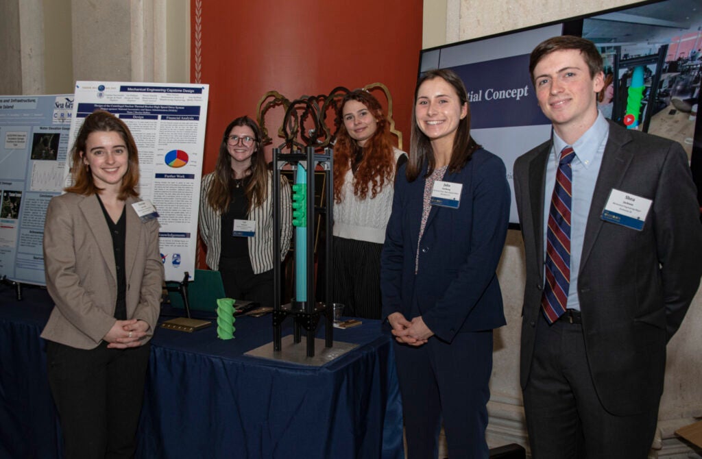 A group photograph of five individuals surrounding a display table
