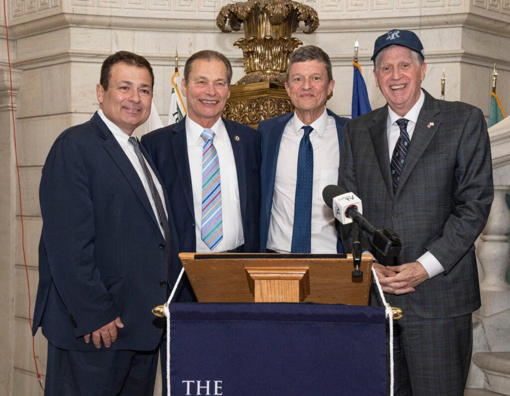 URI President Marc Parlange, RI Governor Daniel McKee, and others stand behind a podium