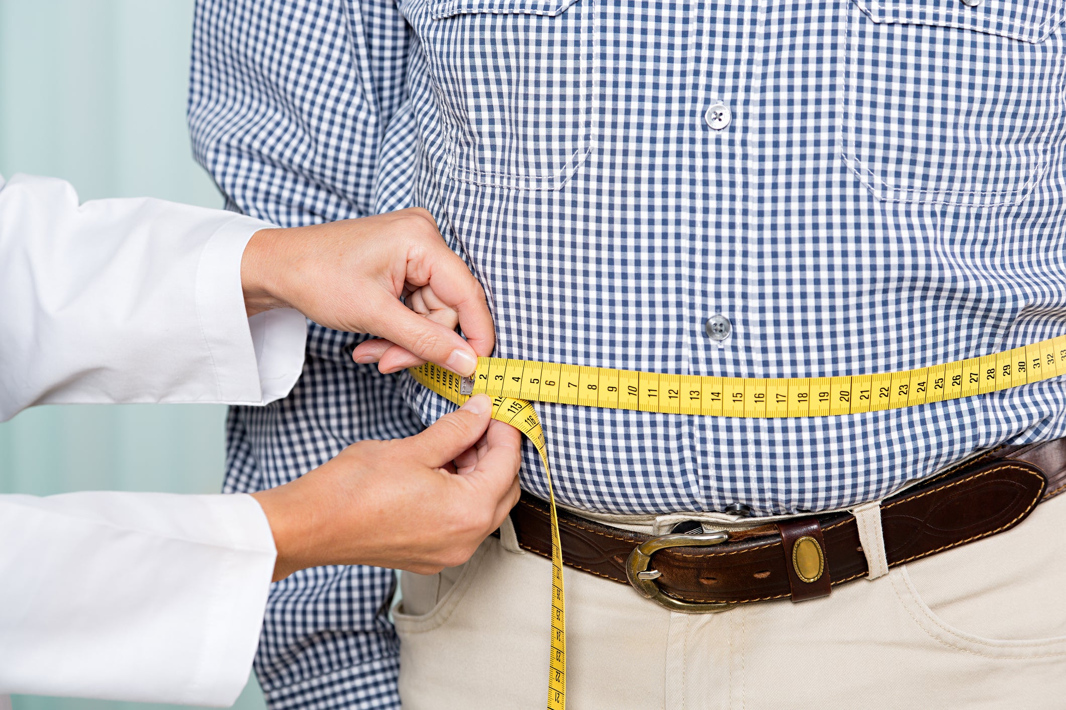 Doctor holds measuring tape around a man's waist