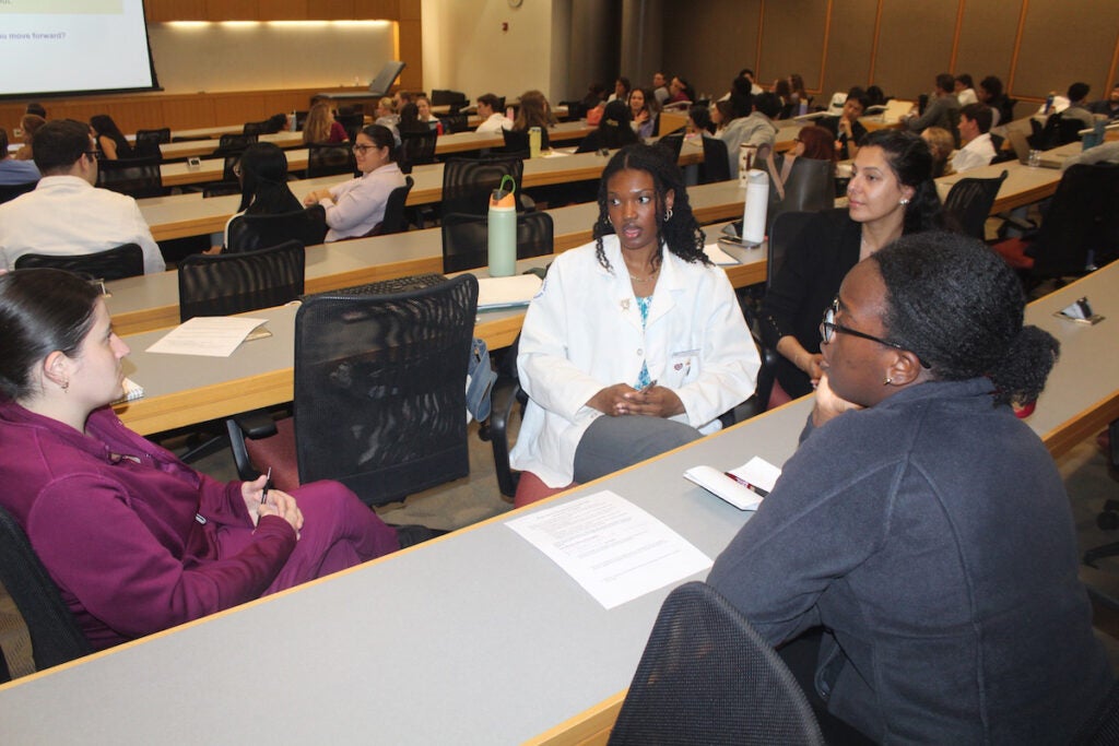 An interdisciplinary team of student healthcare workers discuss patient cases ahead of a simulated patient interaction