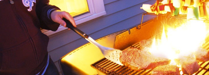 Person grilling steak on a barbecue grill Person grilling steak on a barbecue grill
