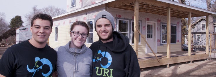 3 URI students in front of the URI-sponsored Habitat for Humanity home