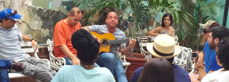 Students listening to man playing guitar