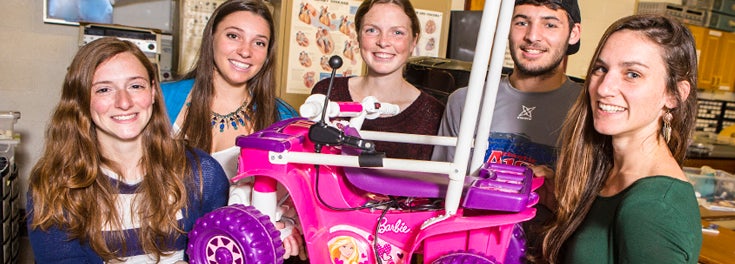 Students and the motorized car they designed for kids with limited movement