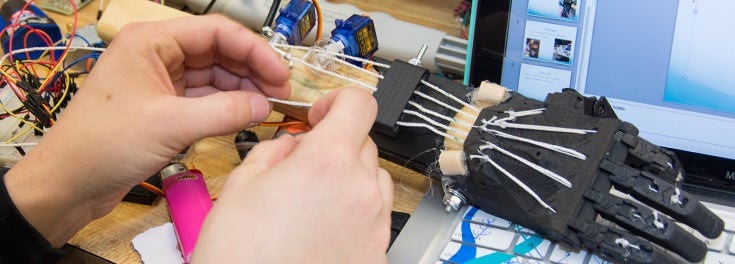 Student's hands building a robotic hand