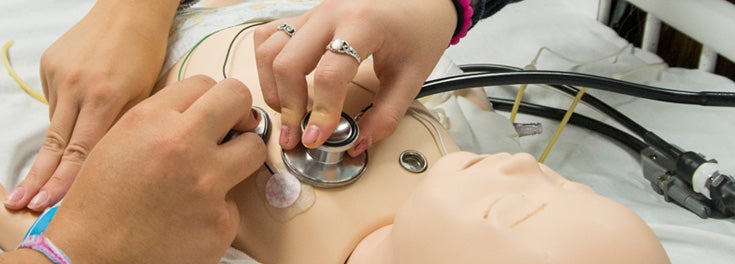 nursing students examining examining baby mannequin