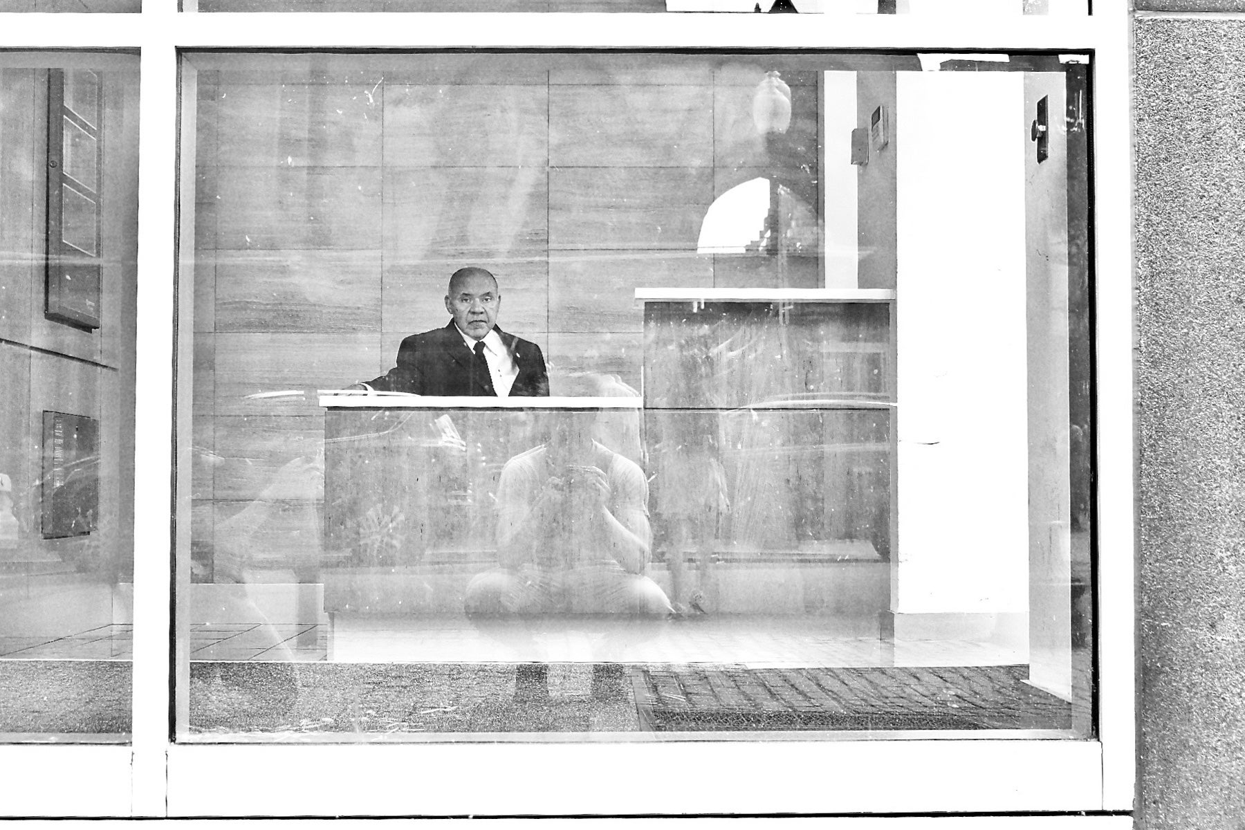 photo of a guard seated behind his desk,separated by glass