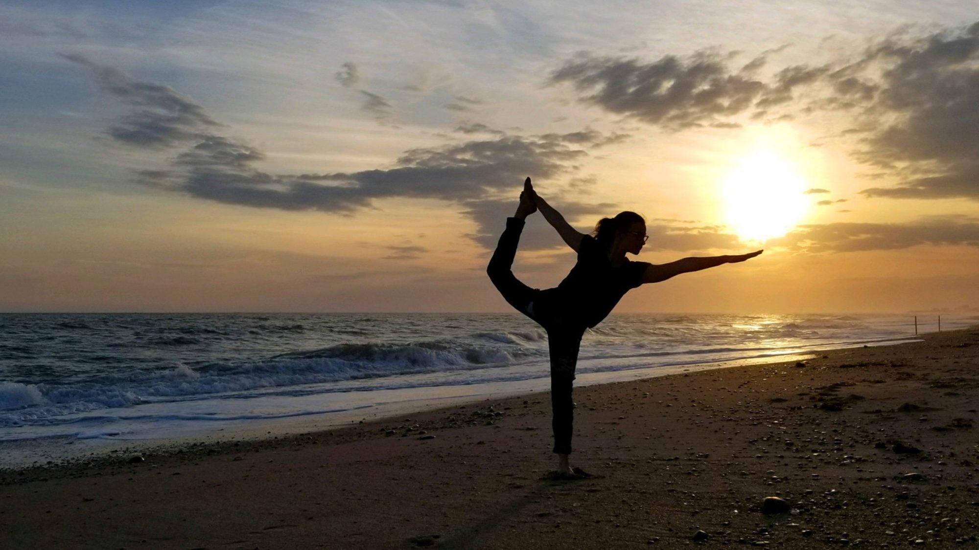 A woman in a yoga pose on a beach