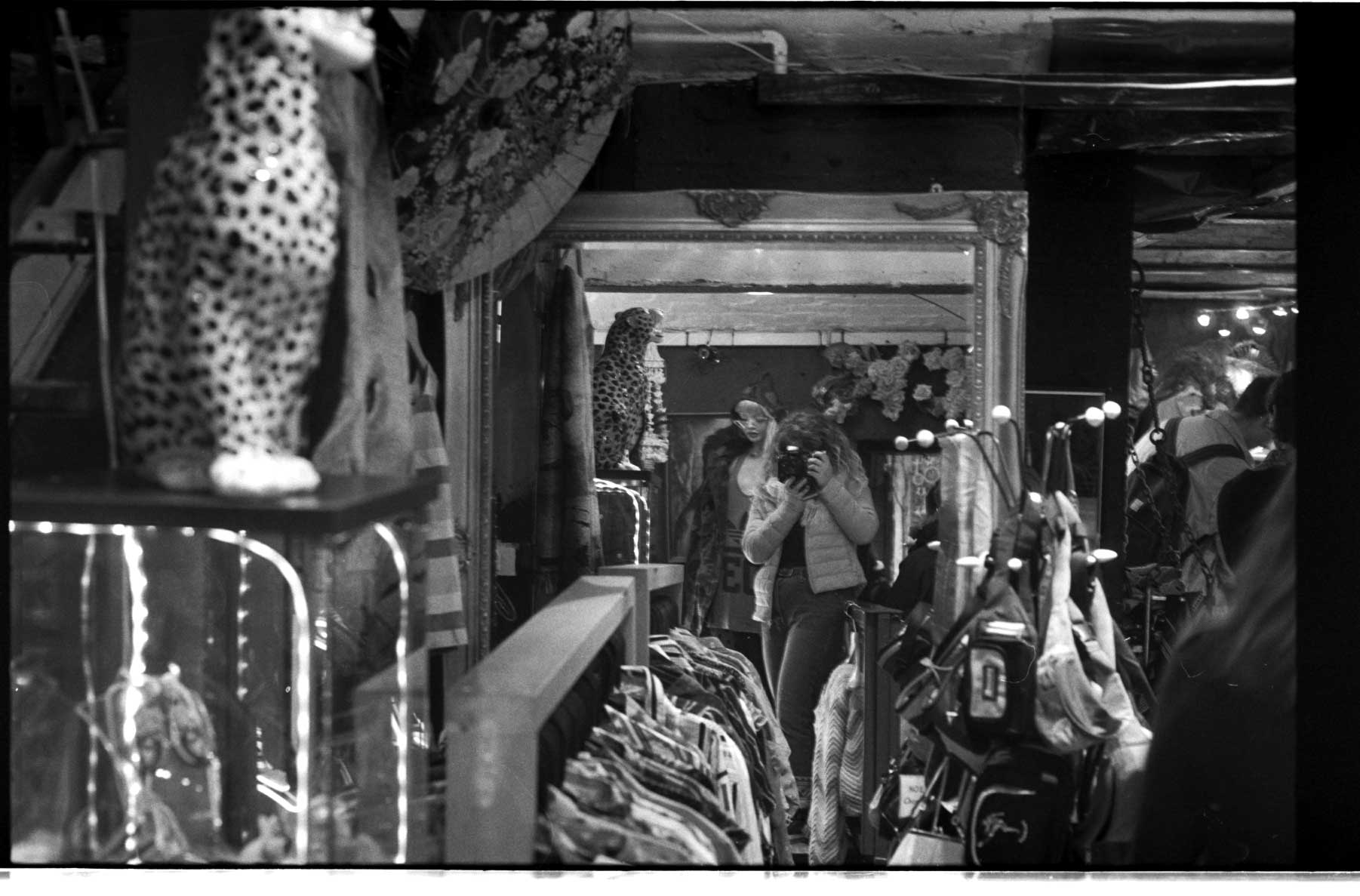 Reflection of a photographer taking a shot of crowded shop