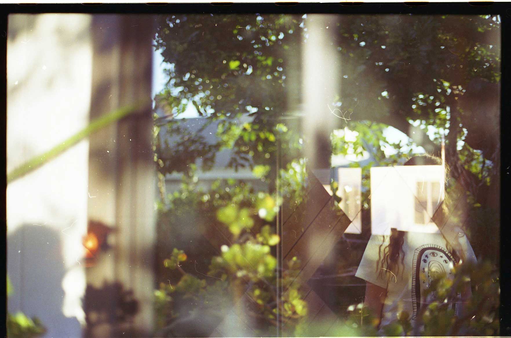 Double exposure of woman looking through trees to the water