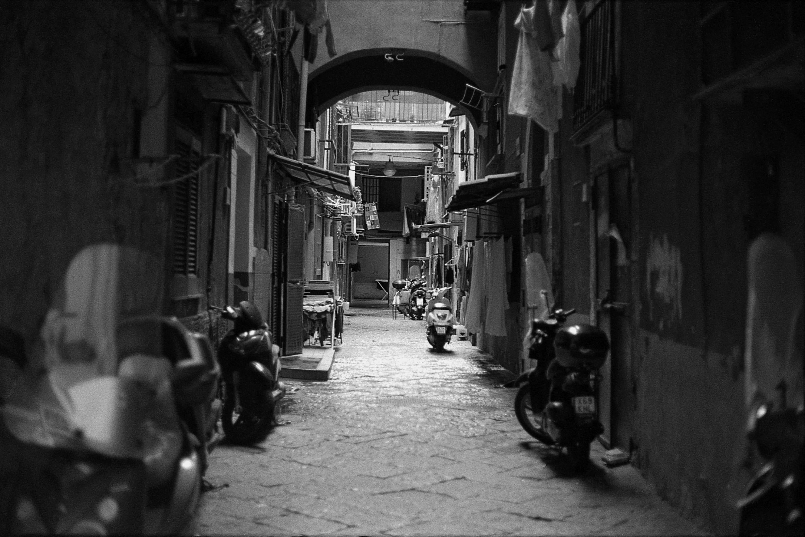 Looking down an narrow alley with motorcycles outside the doorways