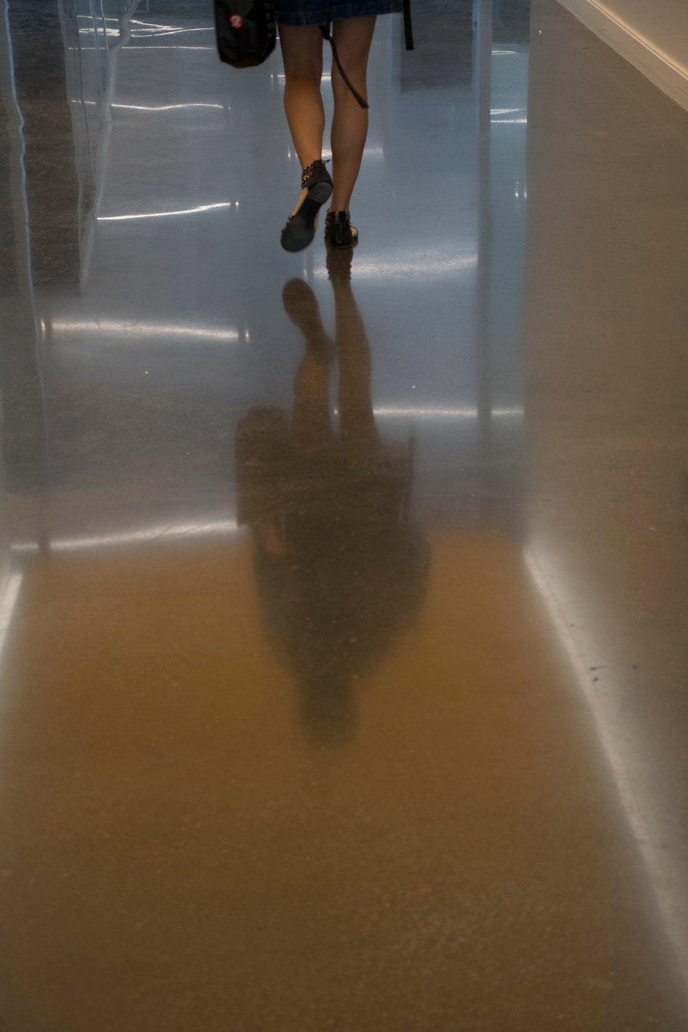 The smooth concrete hallway reflects the lights from the lighting above.