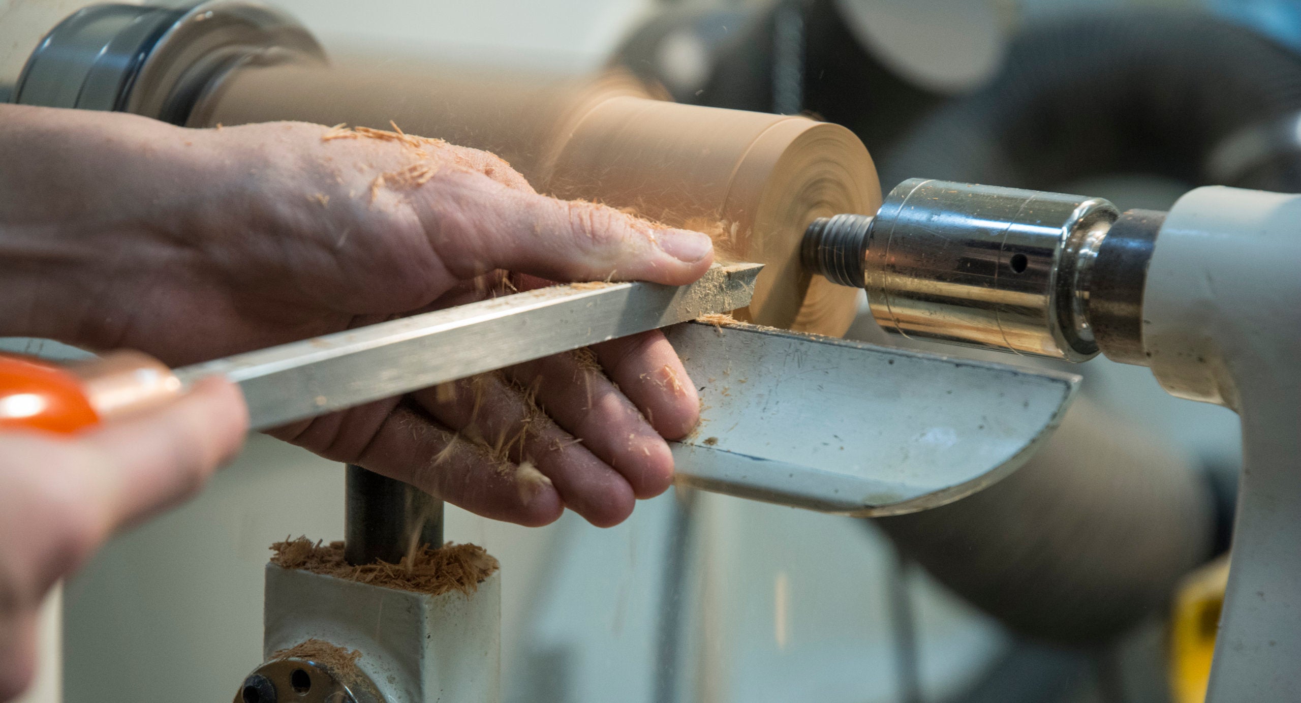 Closeup of hands working with wood on a lathe.