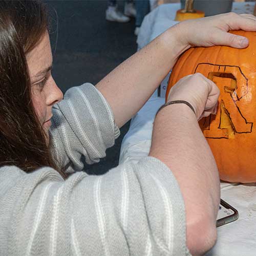 students carving RI logo into pumpkin