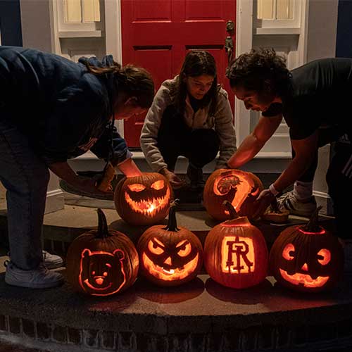 students arranging pumpkins on the steps of President's house