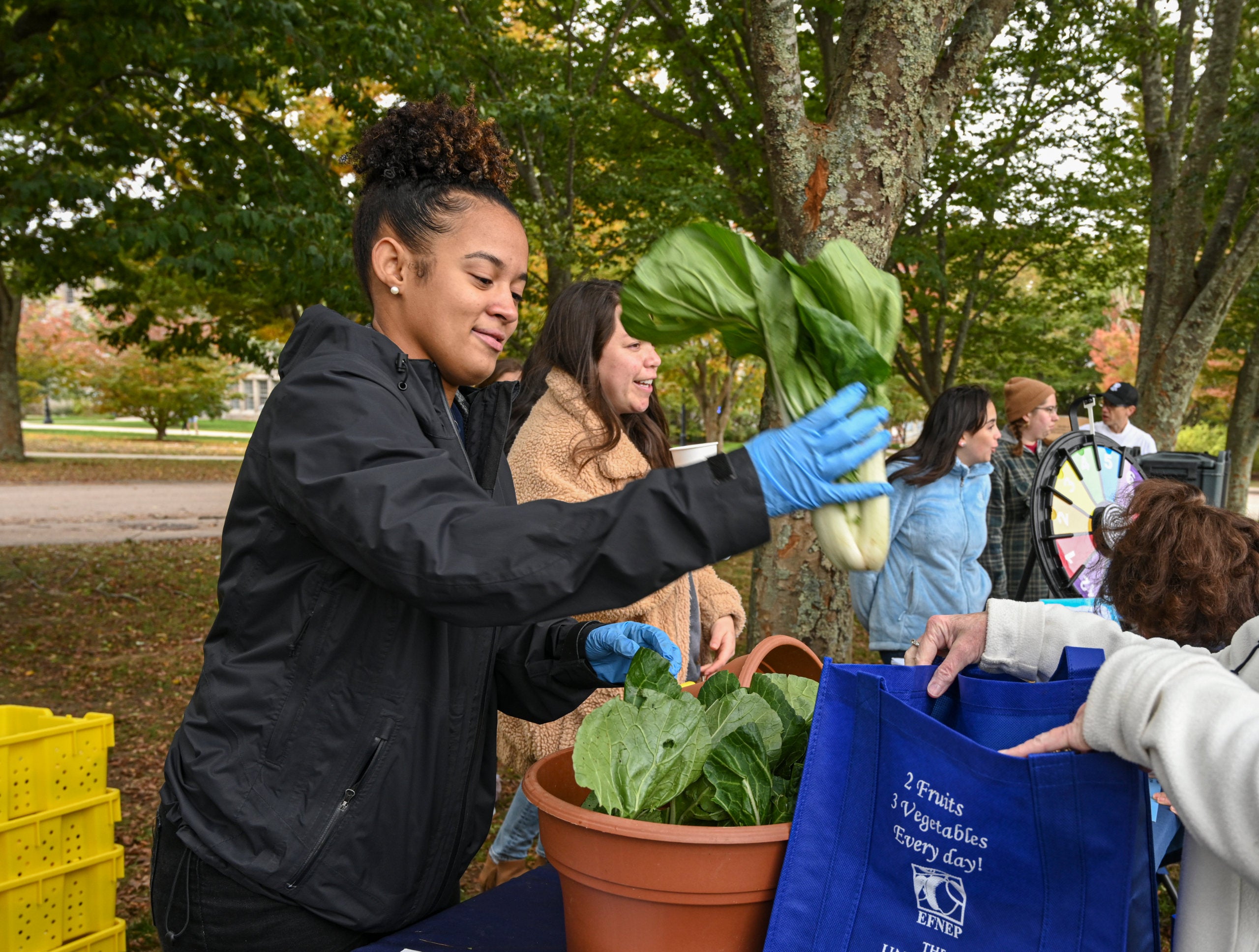 Student volunteer distributing vegetables at the Free Farmers Market