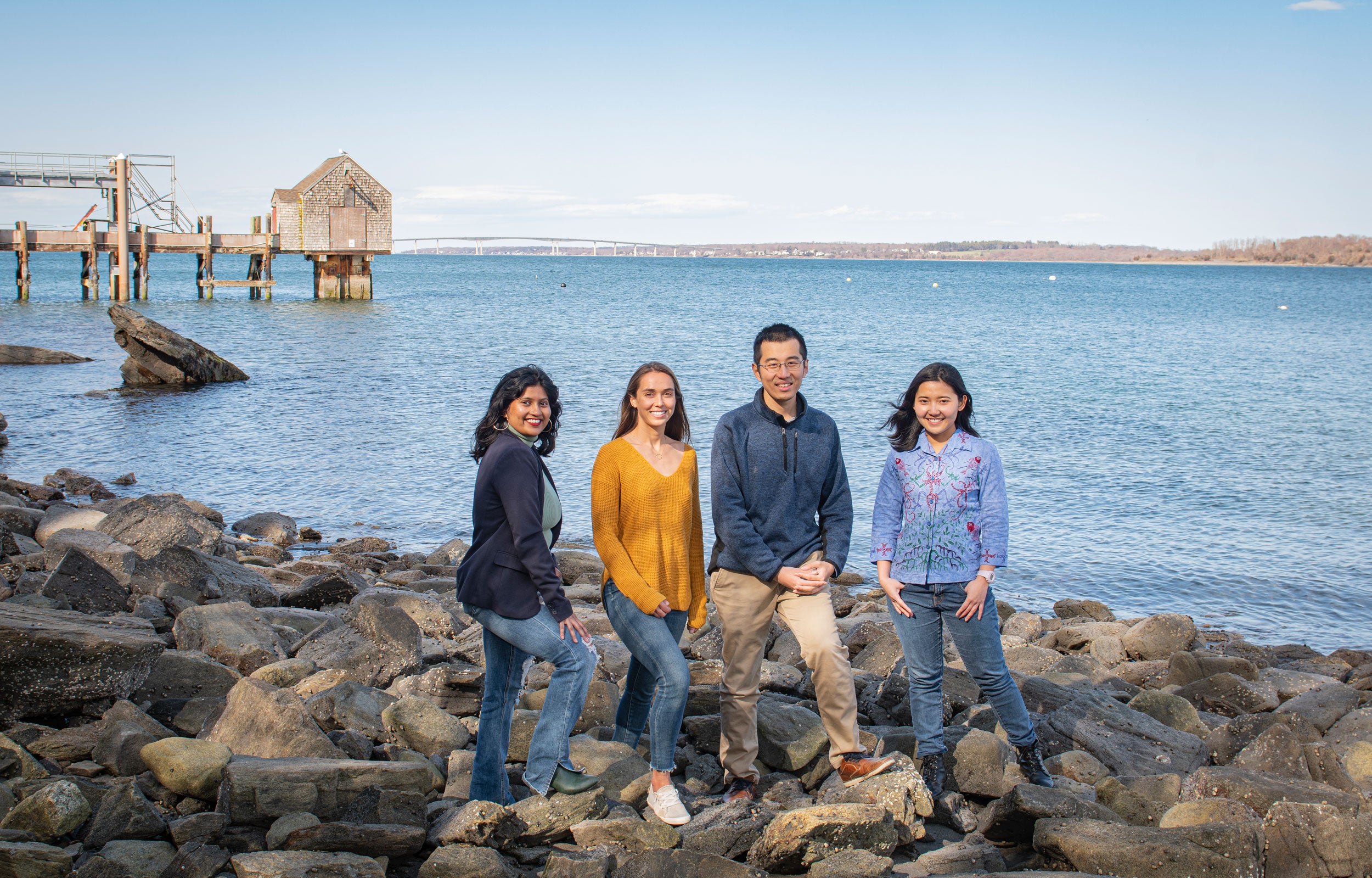 Graduate students participating in Hacking4Oceans project standing on the rocks in front of Narragansett Bay.