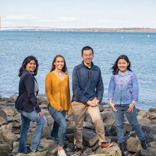 Graduate students participating in Hacking4Oceans project standing on the rocks in front of Narragansett Bay