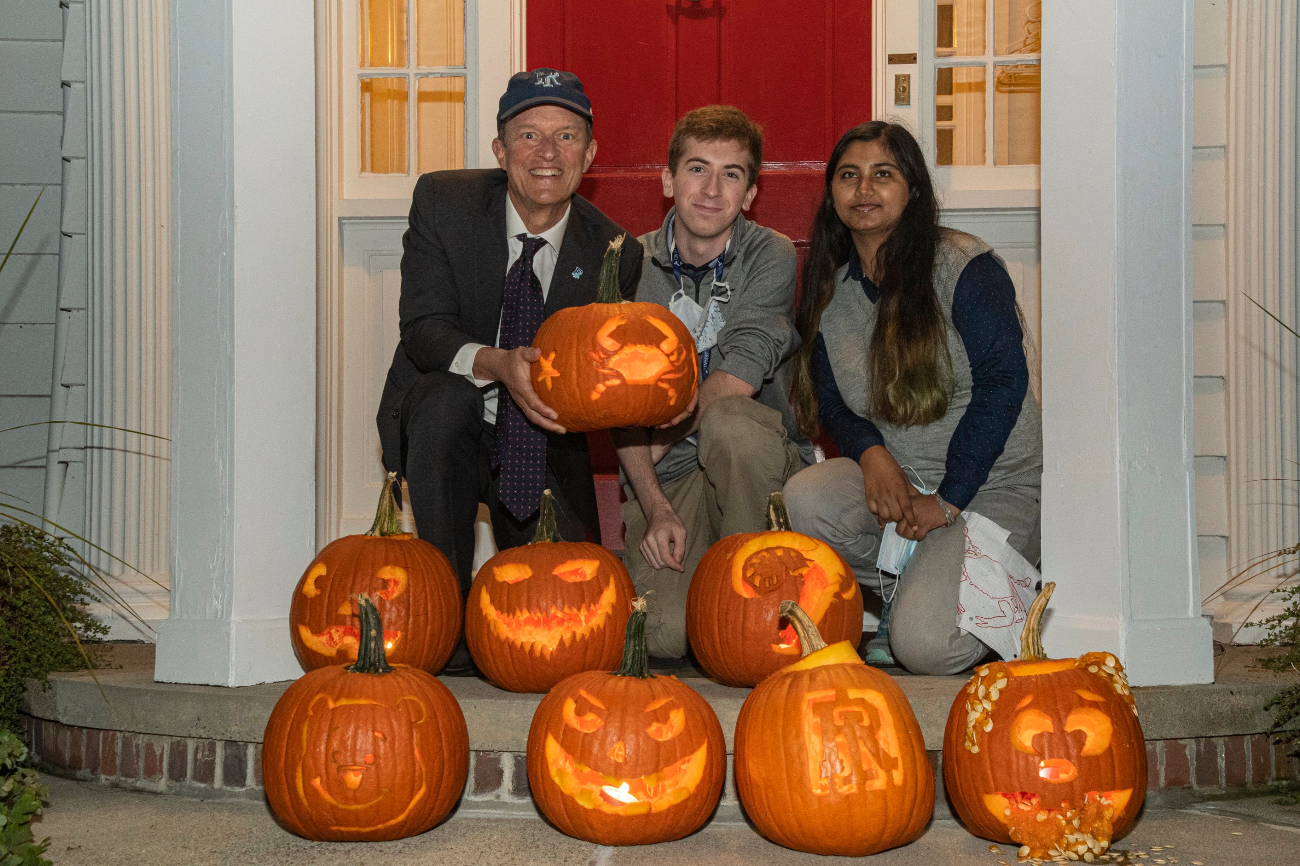 President Marc Parlange sits with two students; carved pumpkins are gathered around them