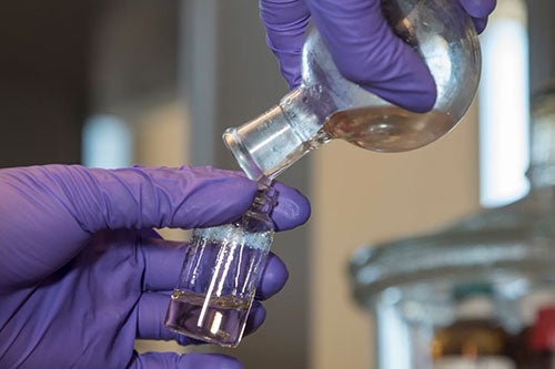 purple gloves pouring liquid lab shot